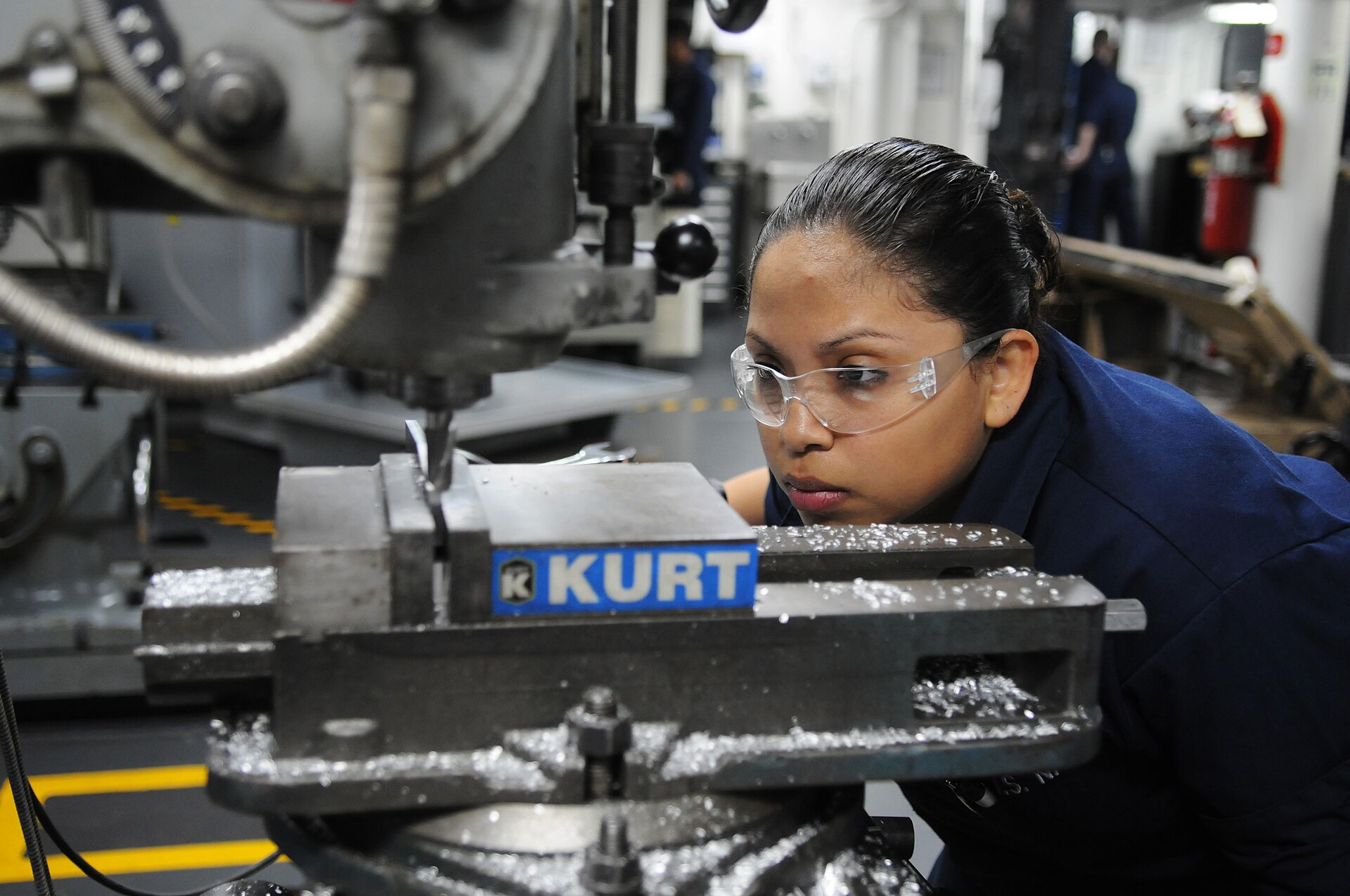 Machinery repair technician operating a milling machine to repair a metal component in an industrial workshop